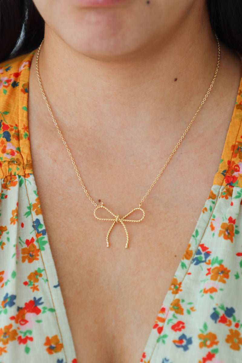 girl wearing gold bow necklace