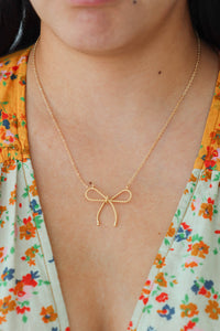 girl wearing gold bow necklace
