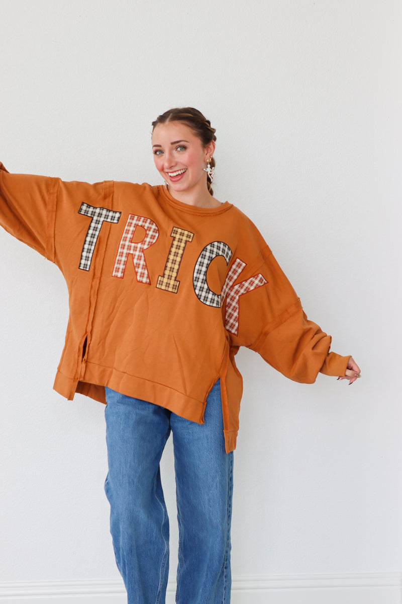 girl wearing orange long sleeve "trick" top