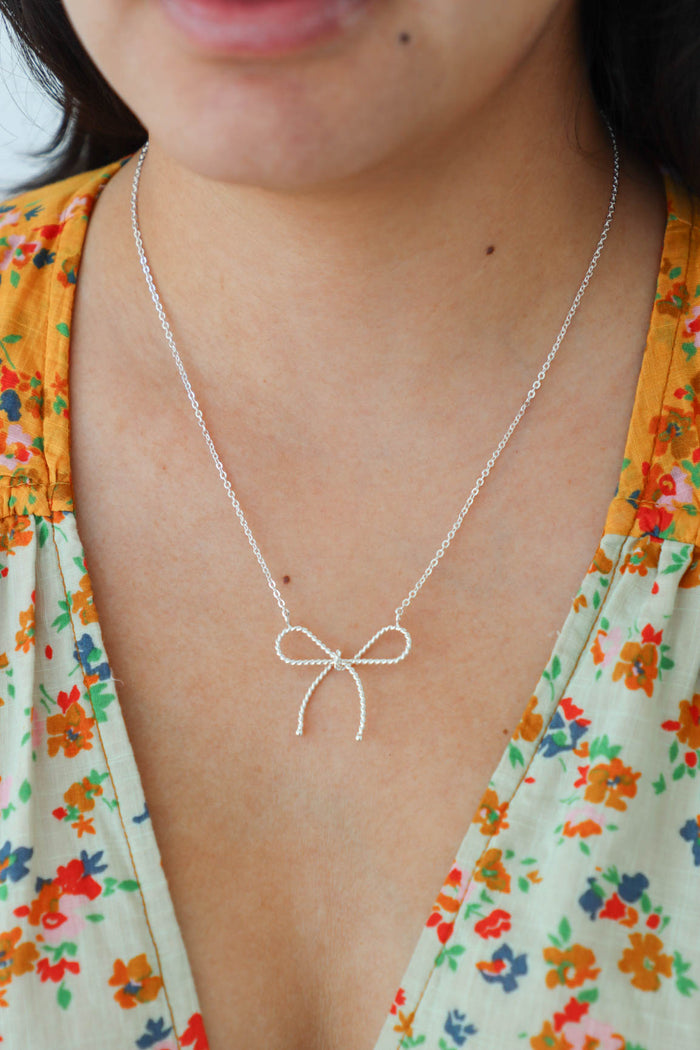 girl wearing silver bow necklace