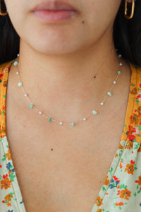 girl wearing gold dainty necklace with blue stone beads