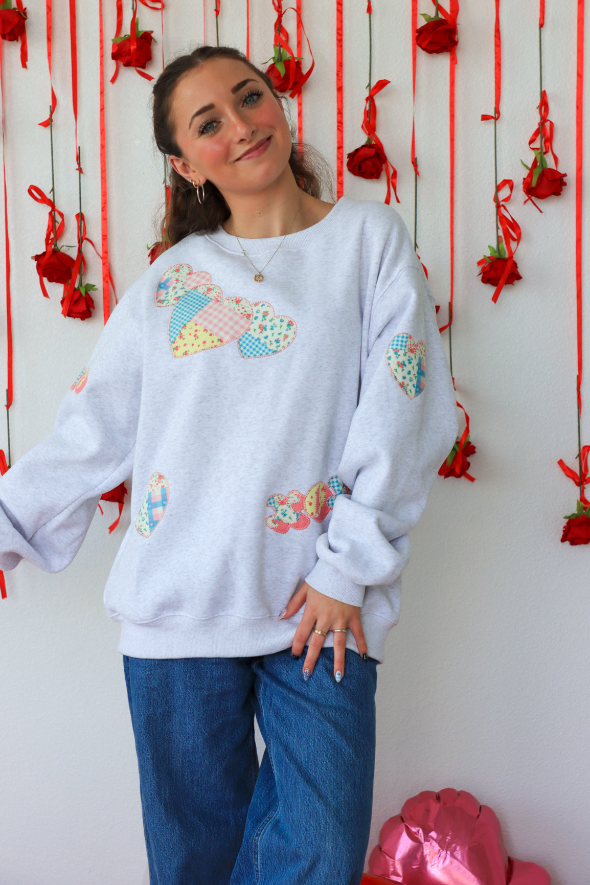 Person wearing a light gray sweatshirt with colorful butterfly designs against a decorative background.