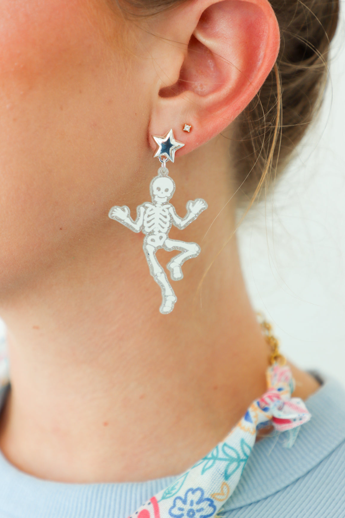Skeletal design earring worn by a person with a neutral background