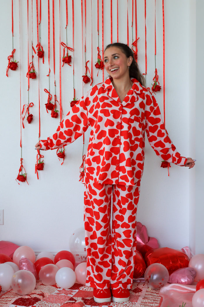 Person wearing a red and white heart-patterned onesie in a room with balloons and decorations.