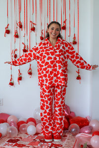 Person wearing a red and white heart-patterned onesie in a decorated room with balloons and hanging decorations.