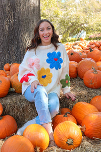 girl wearing cream sweater with large colorful embroidered flower detailing