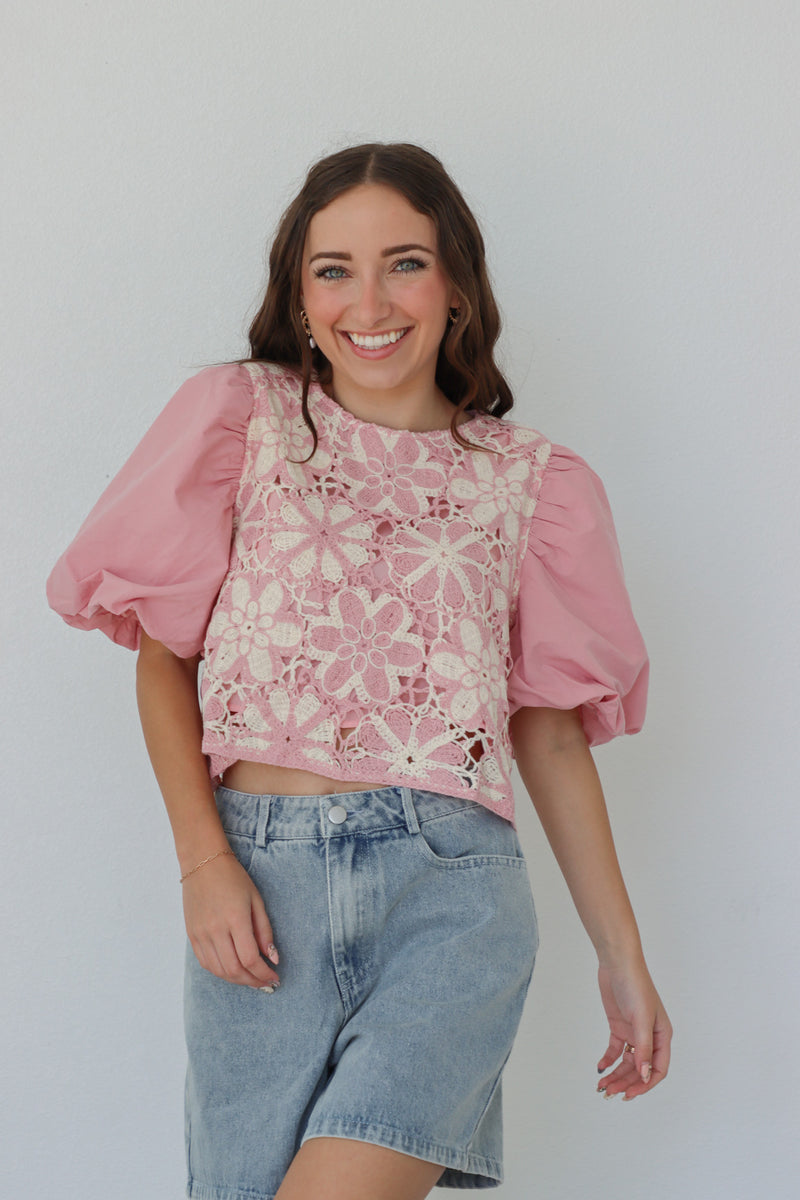 girl wearing pink puff sleeved top with crochet detailing