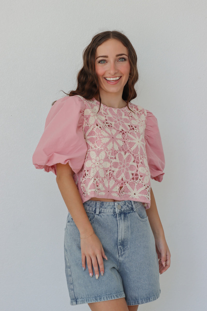 girl wearing pink puff sleeved top with crochet detailing