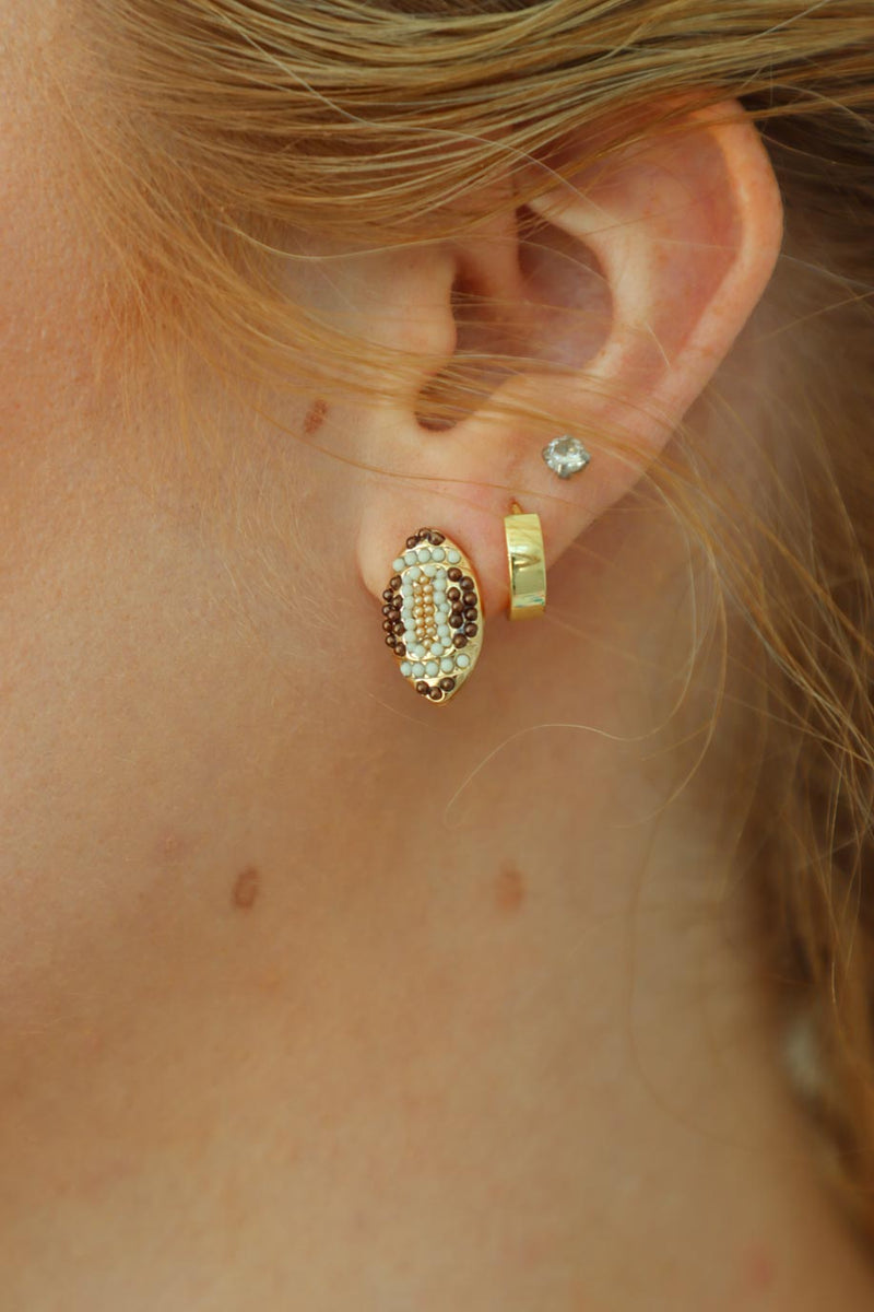 girl wearing football stud earrings