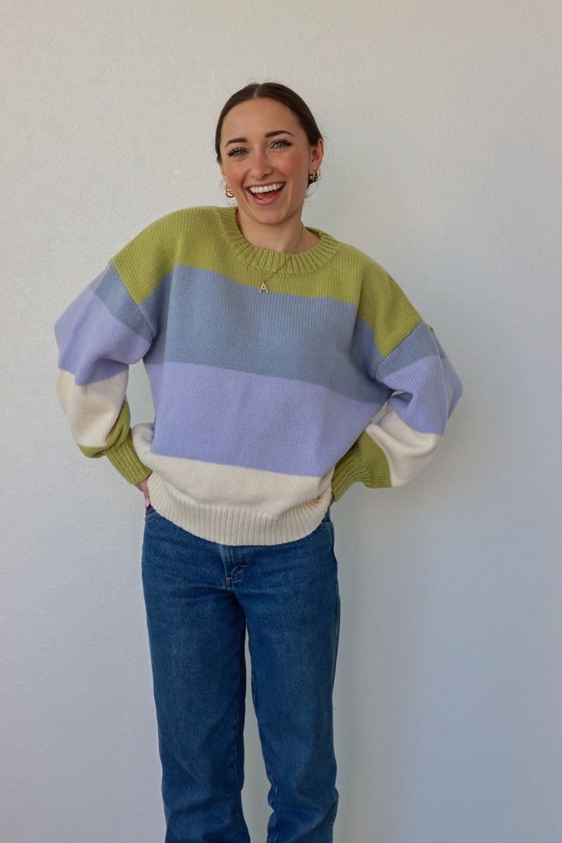 girl wearing blue,green, and cream striped knit sweater