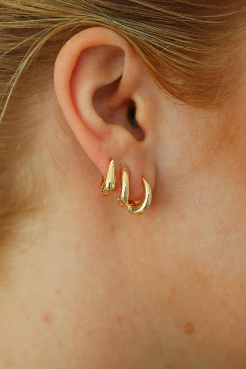 girl wearing three gold hoop huggie earrings