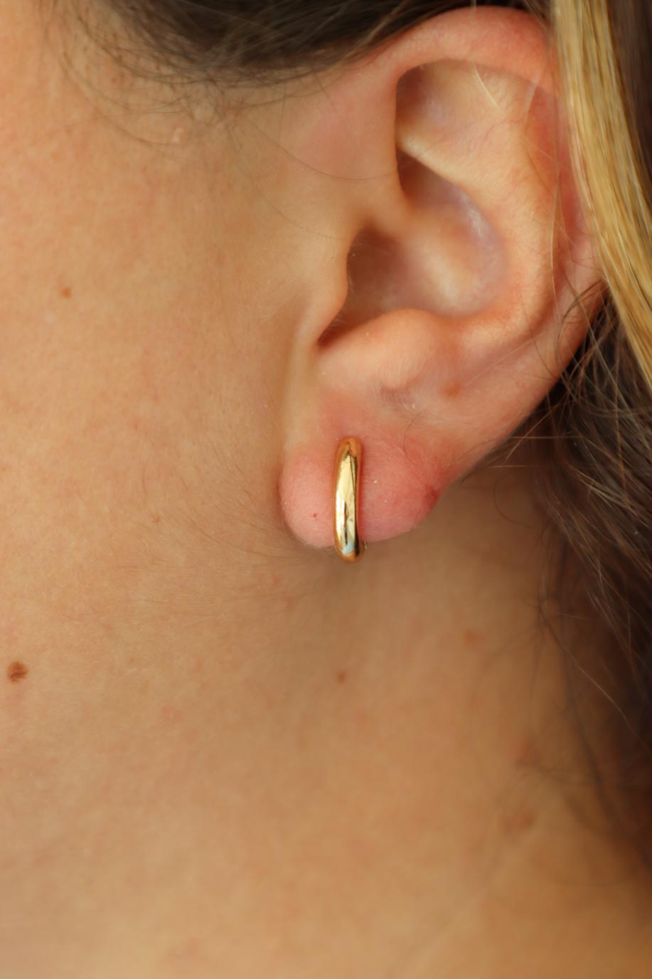 girl wearing gold hoop huggie earrings