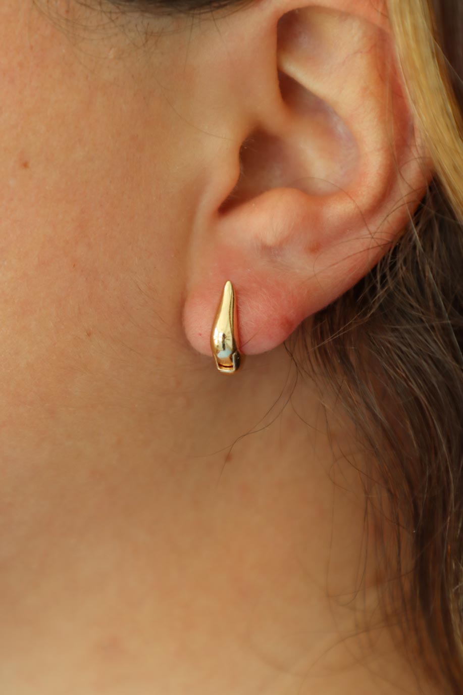 girl wearing gold hoop huggie earrings