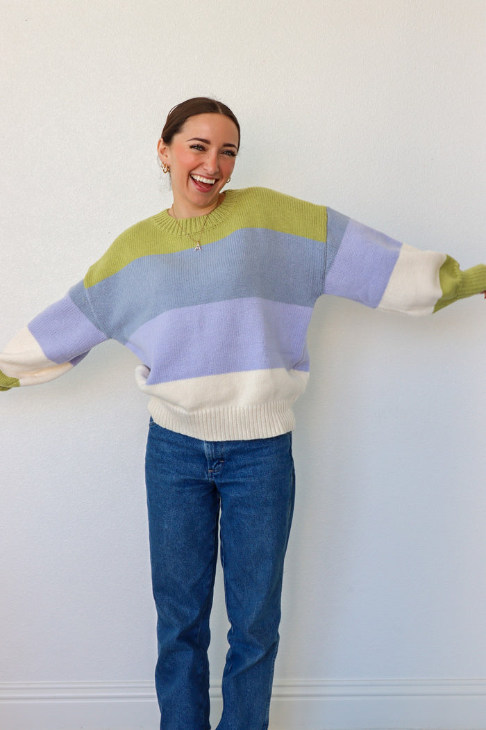 girl wearing blue,green, and cream striped knit sweater