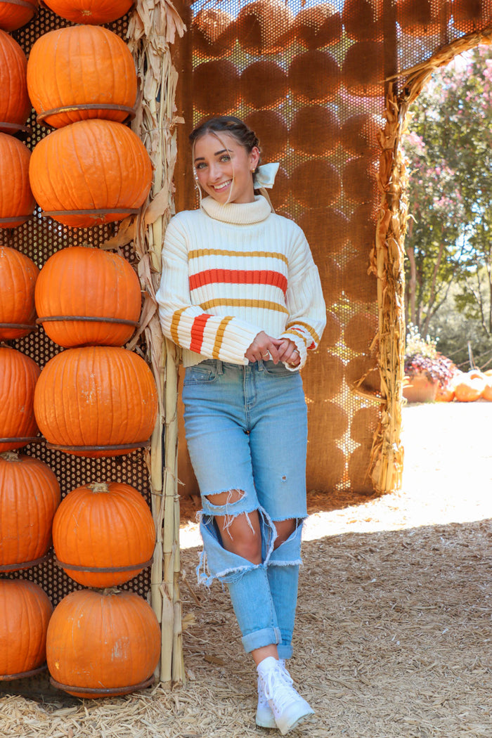 girl wearing cream turtleneck sweater with orange and brown strips