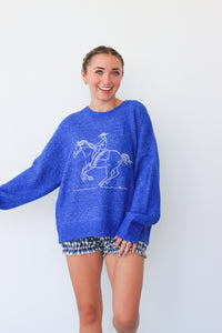 Woman wearing a blue sweater with a horse design on a white background