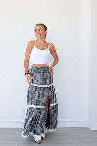 Woman wearing a white sports bra and plaid pants with a high slit on a white background