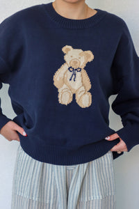 girl wearing navy teddy bear knit sweater