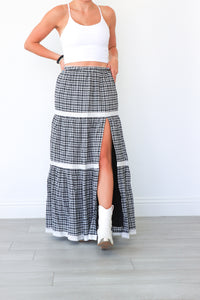 Person wearing a black and white checkered skirt with a white top against a plain background