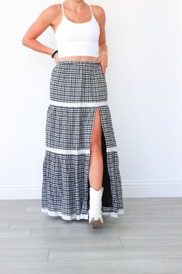 Person wearing a black and white checkered skirt with a white top against a plain background