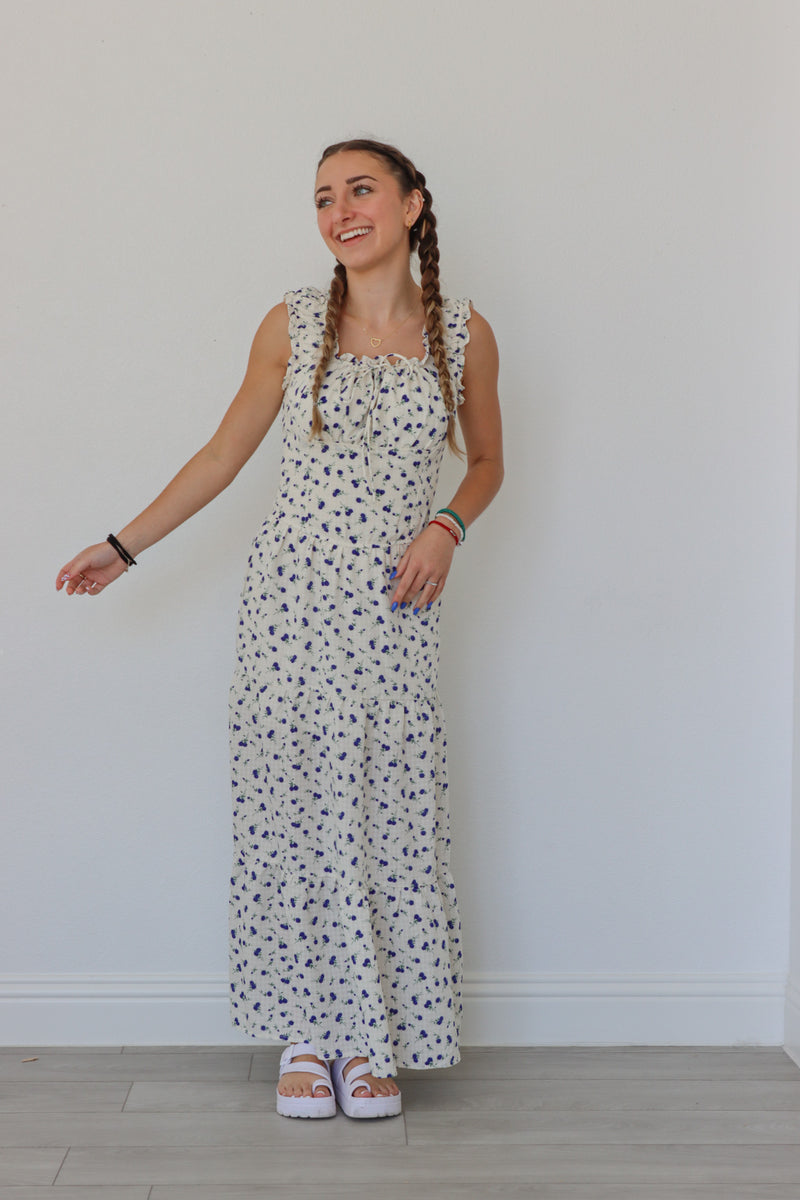 girl wearing white long peasant dress with blue floral pattern