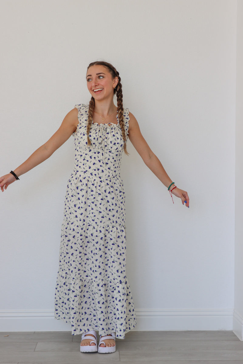 girl wearing white long peasant dress with blue floral pattern