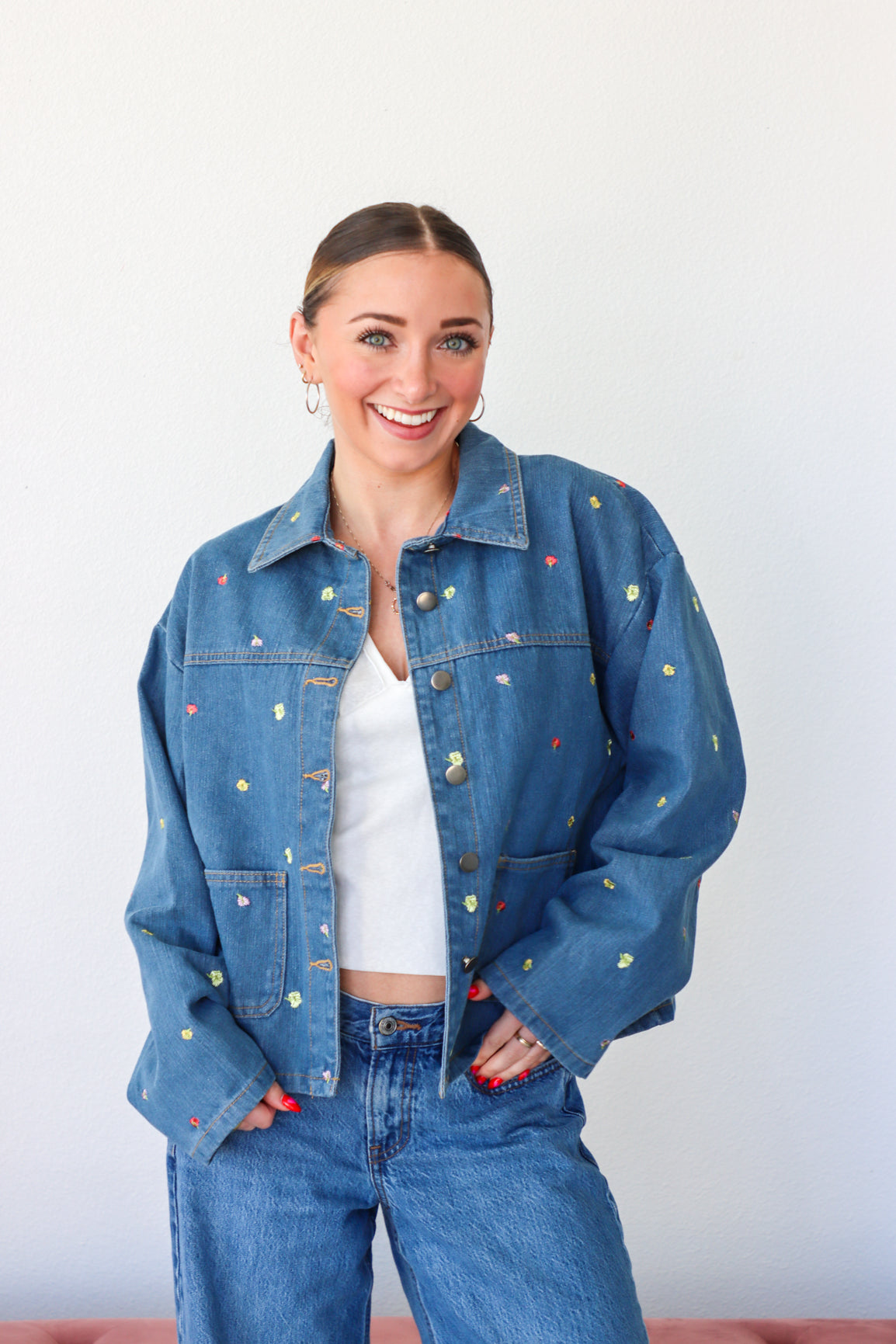Person wearing a blue denim jacket with colorful buttons against a white background