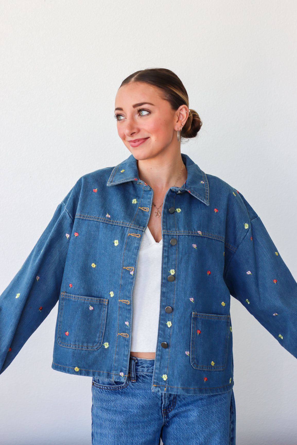 Woman wearing a blue denim jacket with colorful speckles on a white background