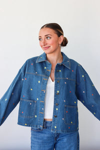 Woman wearing a blue denim jacket with colorful speckles on a white background