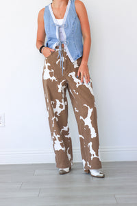 Person wearing brown and white patterned pants with a light blue denim jacket over a white shirt.