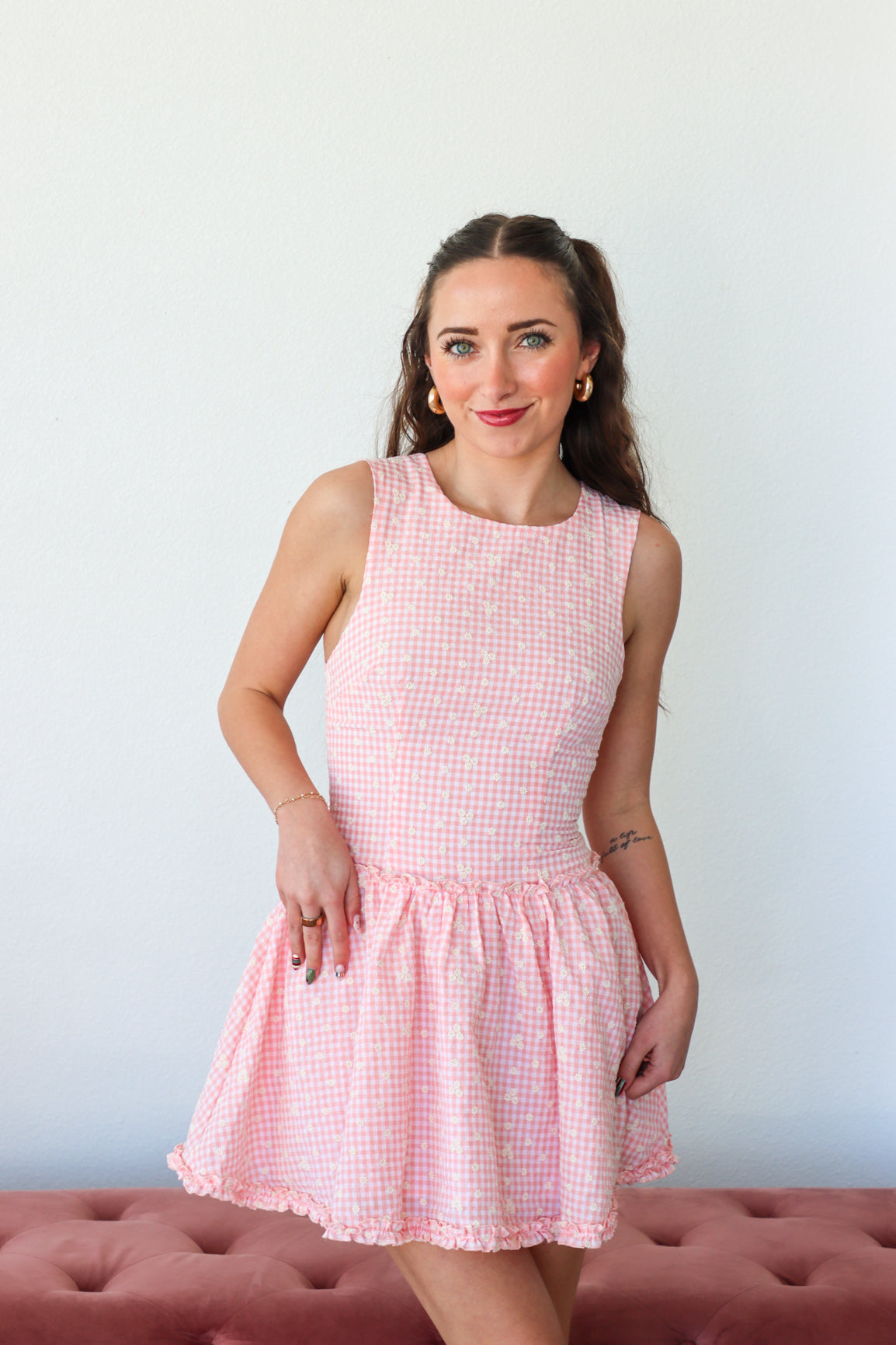 Woman wearing a pink checkered dress against a plain background