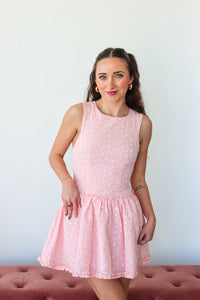 Woman wearing a pink checkered dress against a plain background