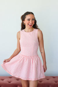 Woman wearing a pink checkered dress against a plain background