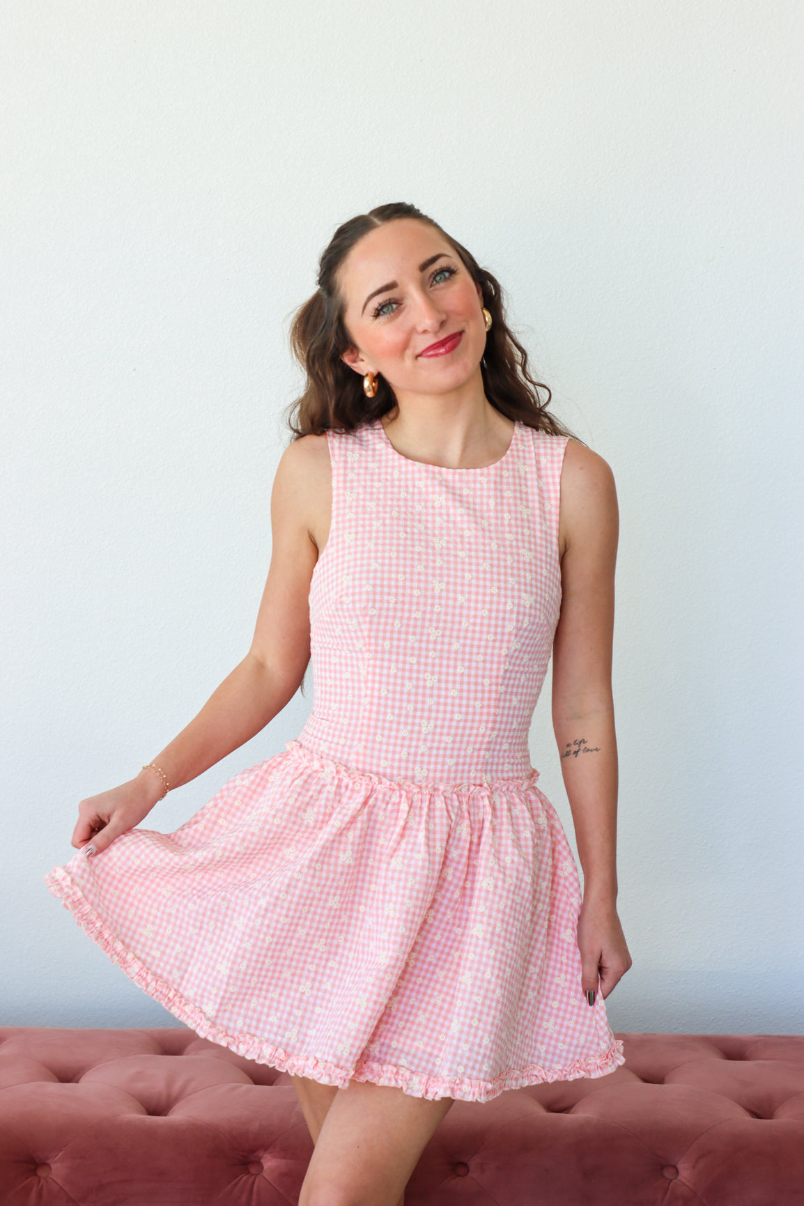 Woman wearing a pink checkered dress against a white background