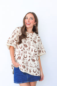 Woman wearing a patterned blouse and denim skirt against a white background