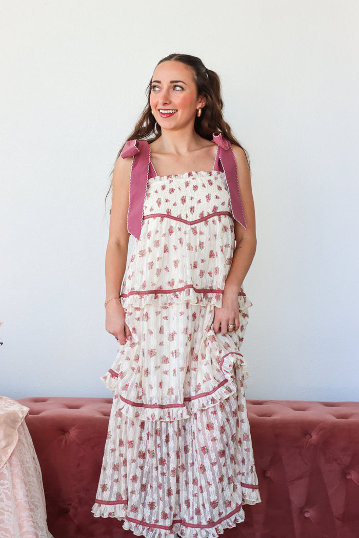 Woman wearing a floral dress with pink accents against a white background
