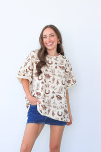 Woman wearing a patterned blouse and denim shorts against a white background