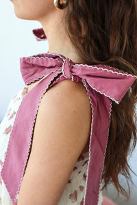 Close-up of a person wearing a pink ruffled top with a floral dress underneath.