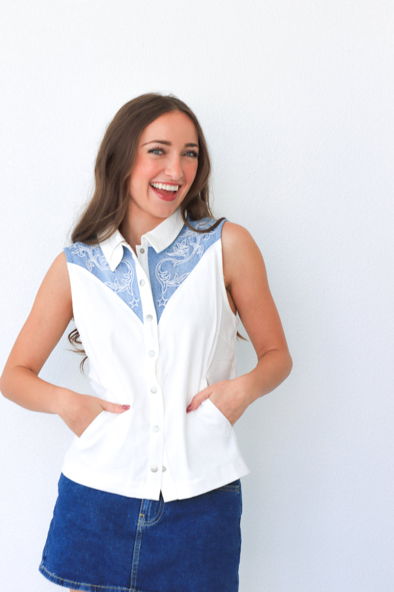 Woman wearing a white blouse with blue lace details against a white background