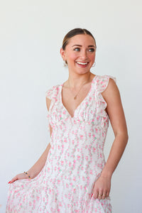 Woman wearing a white floral dress against a plain background