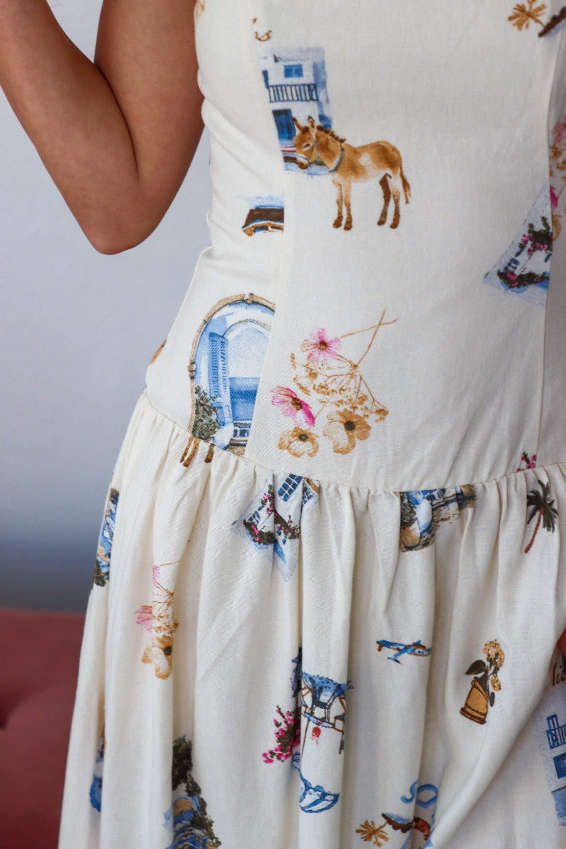 Close-up of a white dress with colorful embroidery patterns on a plain background