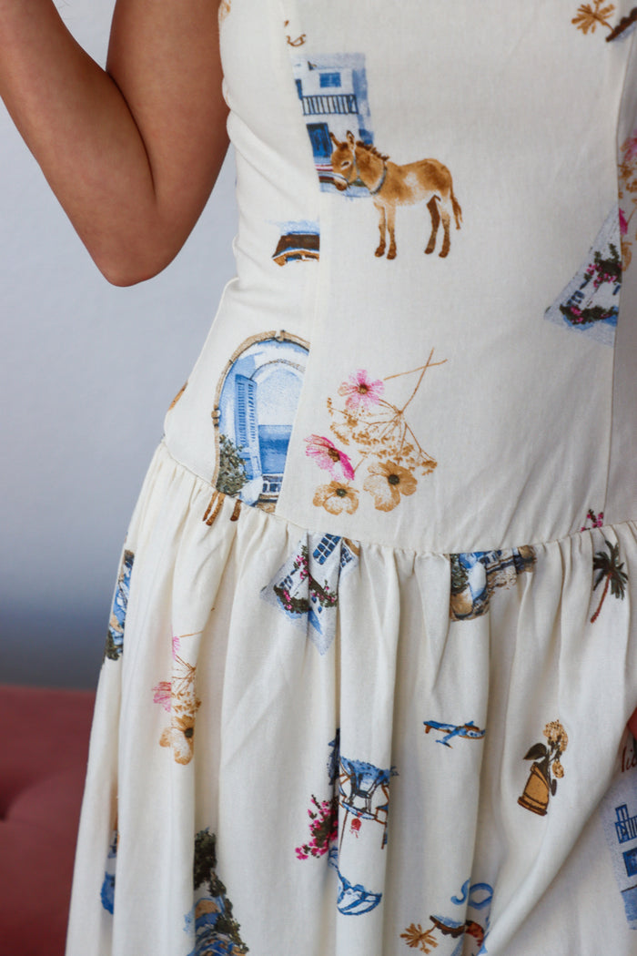 Close-up of a white dress with colorful embroidery patterns on a plain background