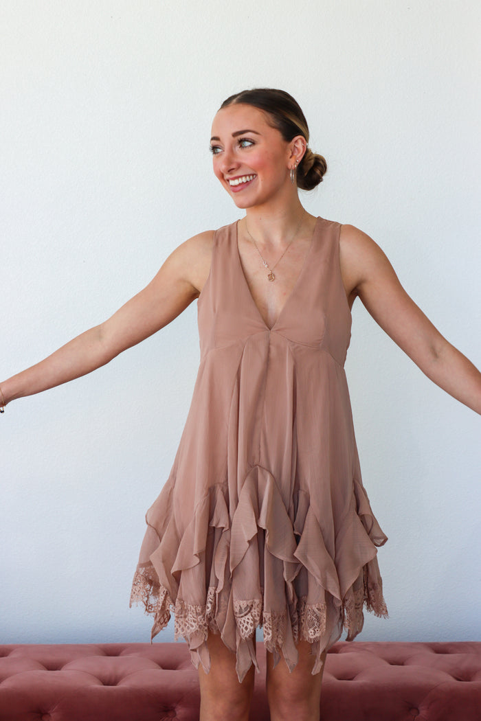 Woman wearing a brown dress with lace details against a white background