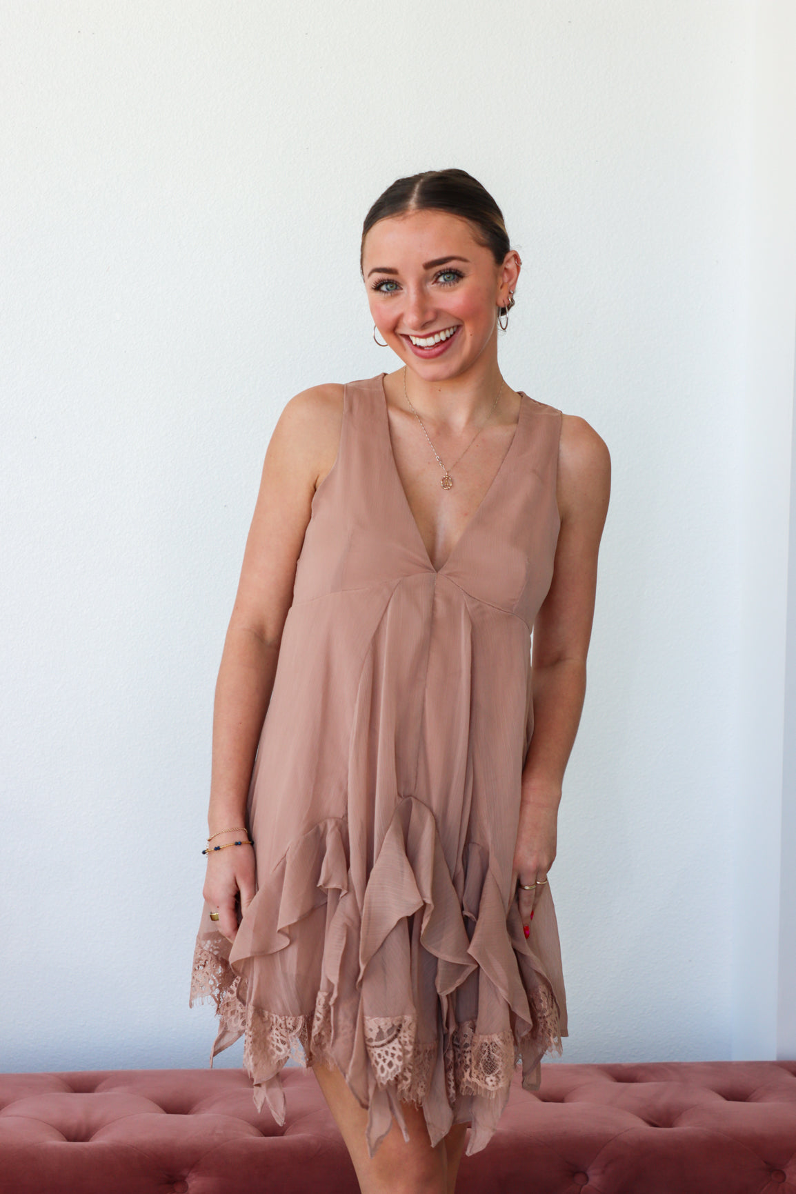 Woman wearing a beige sleeveless dress with lace details against a white background