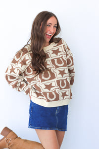 Woman wearing a patterned sweater and denim skirt against a white background