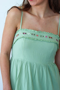 Green dress with floral lace details on a plain background