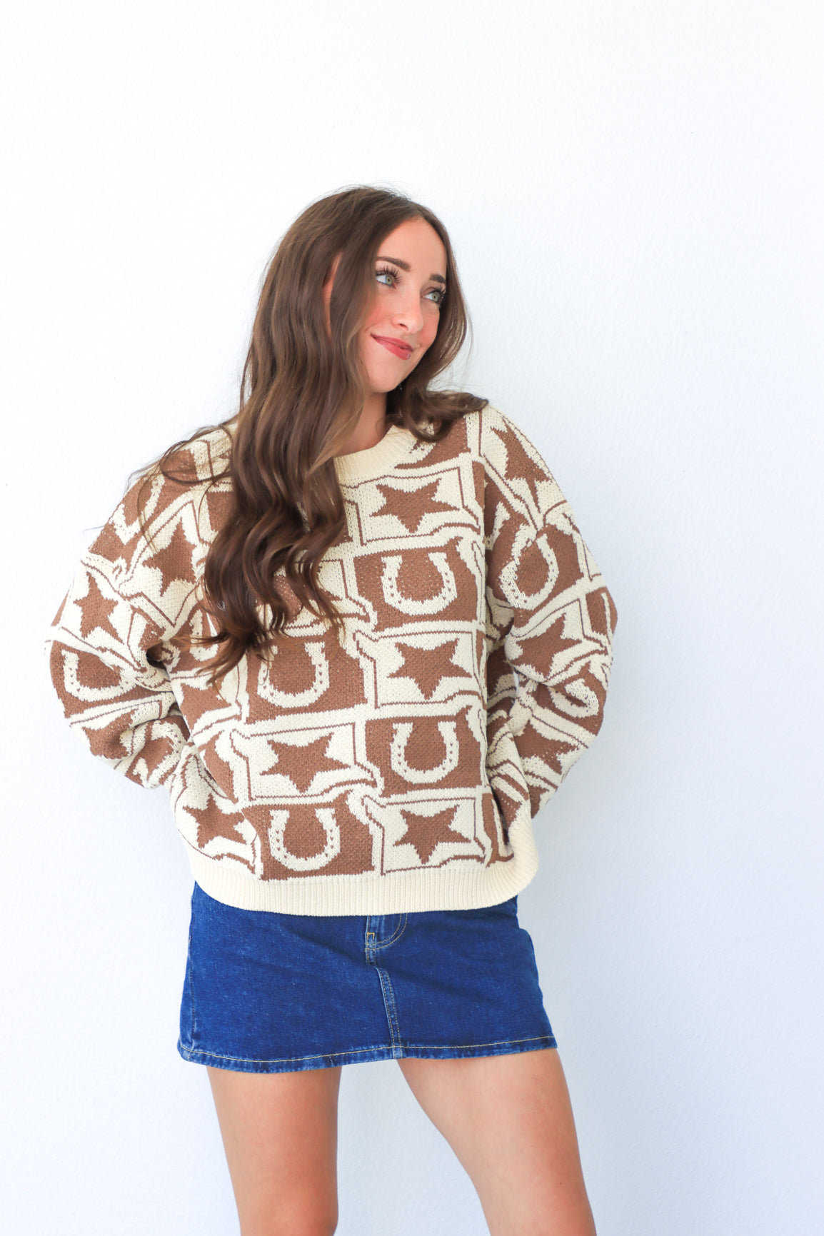 Woman wearing a patterned sweater and denim skirt on a white background