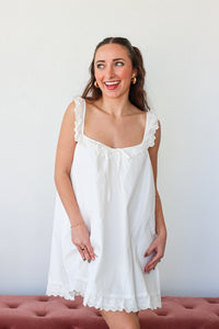 Woman wearing a white lace nightgown against a plain background