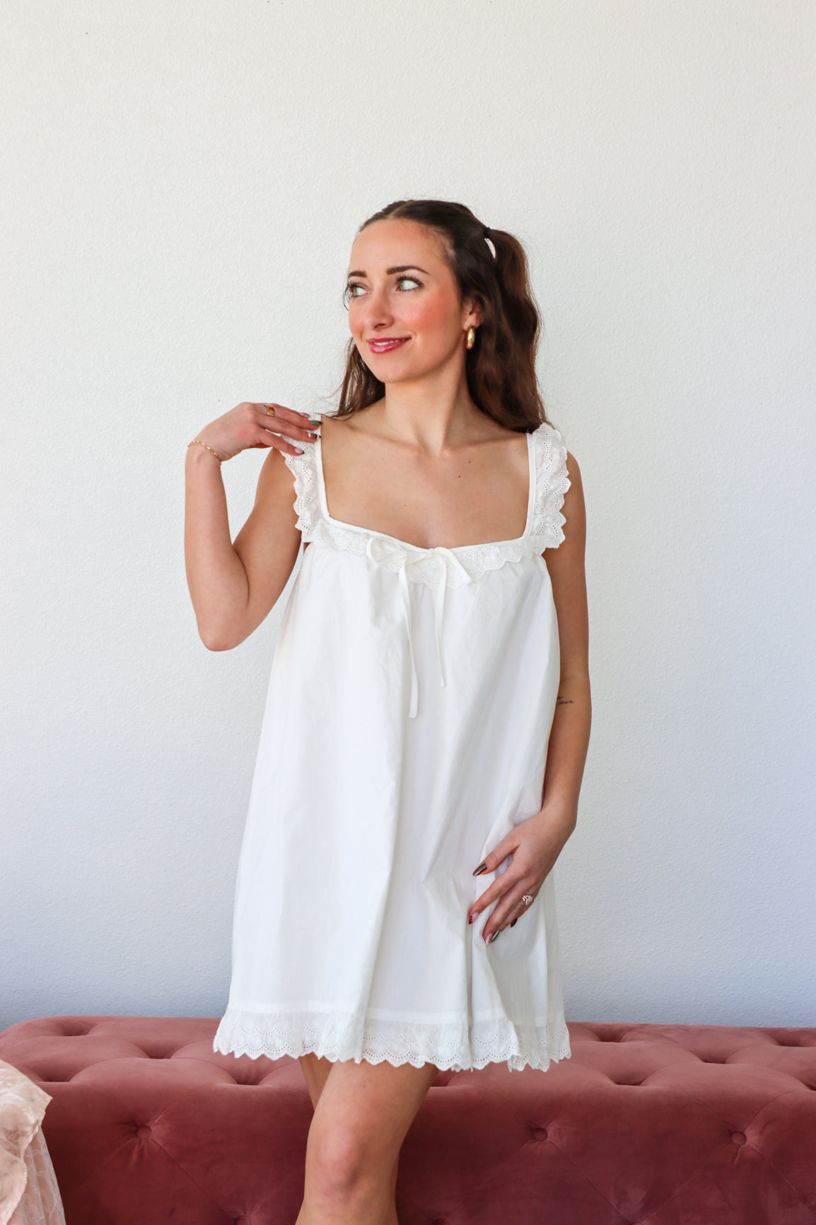 Woman wearing a white nightgown standing against a plain background
