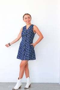 Woman wearing a blue floral dress with white boots against a white background